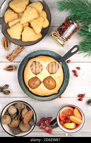 Tavolo festivo con dolci e rami di pino su uno sfondo di legno chiaro. Foto Stock