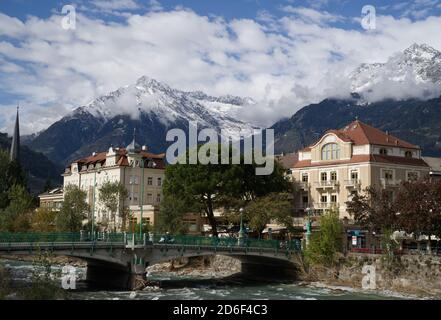 Terme di Merano in Italia in autunno, 15 ottobre 2020. Ponte sul fiume Passer in primo piano, Alpi coperte di neve sullo sfondo. Foto Stock