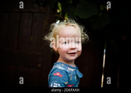 Ragazzo biondo di due anni in Pajamas sorridente per la macchina fotografica Foto Stock