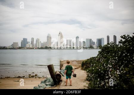 Boy di sei anni in piedi e guardando San Diego Skyline da Coronado Foto Stock