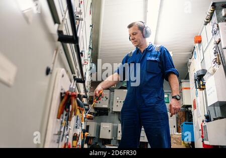 Responsabile tecnico marino nella sala di controllo motore ECR. Lavora in officina Foto Stock