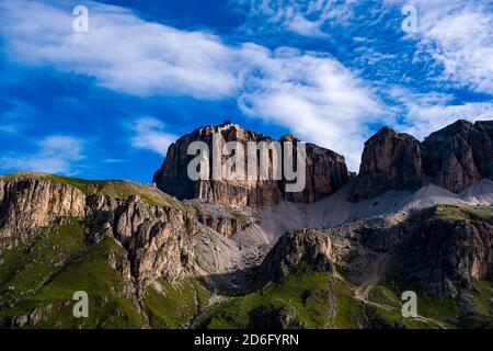 Ripide scogliere rocciose dell'altopiano Sass Pordoi e la stazione della funivia in cima, visto da vicino al passo Pordoi, Passo Pordoi. Foto Stock
