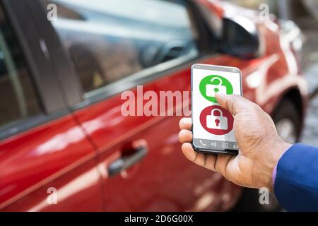 African Man sbloccare l'auto utilizzando l'app per smartphone Foto Stock