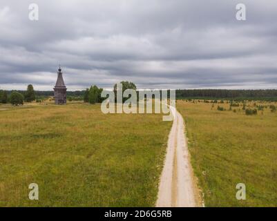 Agosto, 2020 - Lag rosso. Abbandonata alta chiesa in legno nel mezzo di un grande campo. Russia, regione di Arkhangelsk Foto Stock