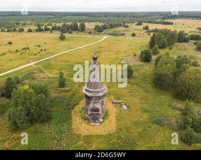 Agosto, 2020 - Lag rosso. Abbandonata alta chiesa in legno nel mezzo di un grande campo. Russia, regione di Arkhangelsk Foto Stock