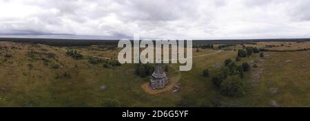 Agosto, 2020 - Lag rosso. Abbandonata alta chiesa in legno nel mezzo di un grande campo. Russia, regione di Arkhangelsk Foto Stock