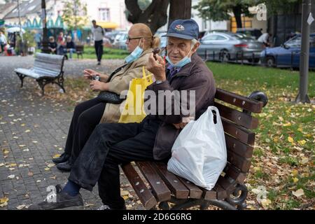 Belgrado, Serbia, 11 ottobre 2020: Donna seduta su una panchina fumando sigaretta accanto ad un uomo fumando pipa Foto Stock