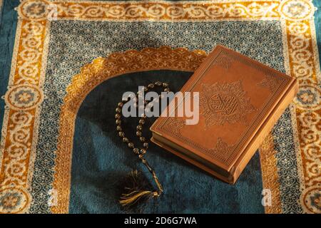 Rosary e Noble Quran sul tappeto di preghiera con luce naturale Foto Stock