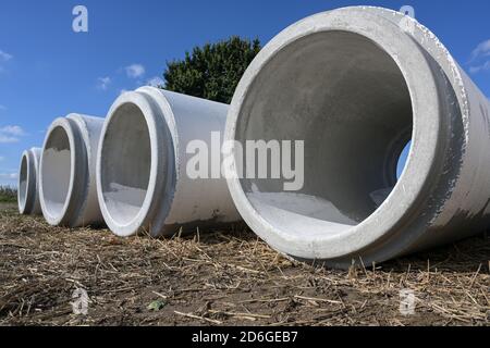 Grandi tubi d'acqua da cemento che si trovano fianco a fianco su un cantiere per costruire un sistema fognario di drenaggio contro l'allagamento, copia spazio, selezionato foc Foto Stock