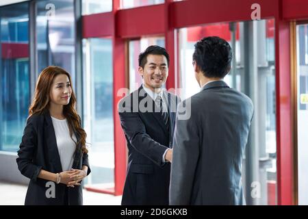 i dirigenti aziendali asiatici scuotono le mani con i clienti in visita in ascensore hall di un moderno edificio per uffici Foto Stock