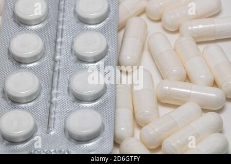 Immagine ravvicinata ad alto angolo di varie pillole bianche su sfondo bianco. Alcuni di loro sono fuori fuoco. Business farmaceutico e vendita di farmaci concetti Foto Stock