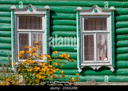 Due finestre nel muro verde di una vecchia casa di tronchi. Kaluga Oblast, Russia. Foto Stock