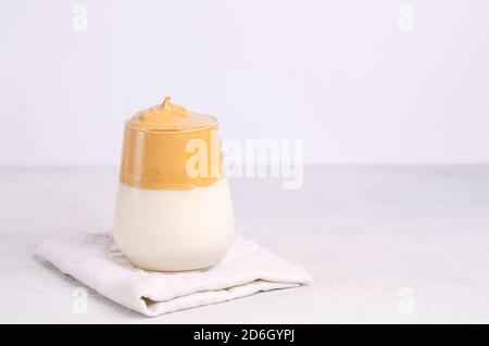 Caffè Dalgon in un telaio di vetro fatto di caffè istantaneo, zucchero, acqua calda e latte, una nuova bevanda fredda alla moda su uno sfondo chiaro. Spazio di copia, disposizione piatta, Foto Stock