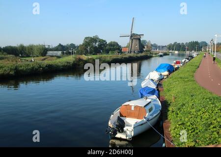 La vista dalla campagna olandese presso la città di Alkmaar nei Paesi Bassi. Il canale con i mulini a vento vicino alla città. Foto Stock