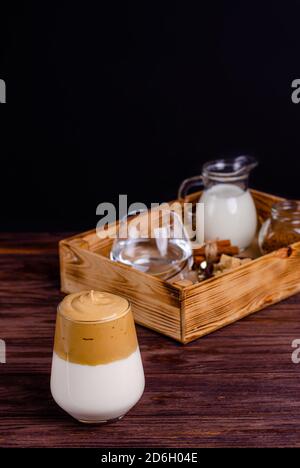 Caffè Dalgon con ingredienti per la sua preparazione in una scatola su fondo di legno. Caffè istantaneo, anice, cannella, zucchero di canna, latte, acqua. Copia spa Foto Stock