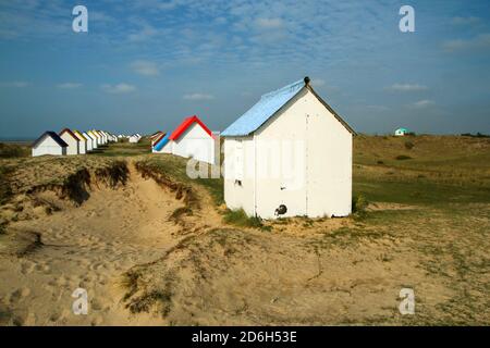 Le piccole case bianche spiaggia con tetti colorati su una spiaggia di Gouville-sur-Mer in Francia in Normandia. L'attrazione per i turisti. Foto Stock