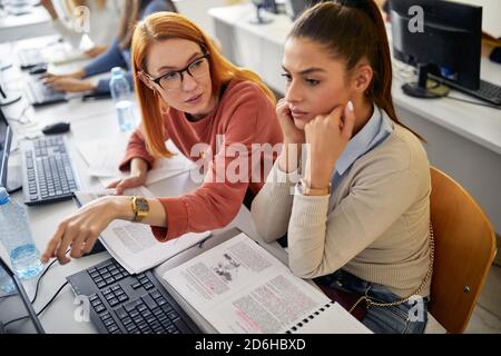 Una studentessa che si preoccupa di una lezione di informatica dura in classe informatica universitaria. I giovani intelligenti studiano all'università. Istruzione, coll Foto Stock