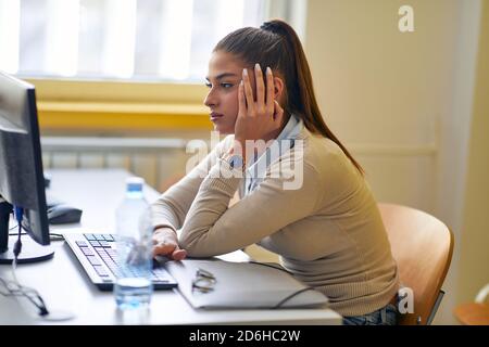 Una studentessa si è preoccupata di una lezione difficile in classe universitaria. I giovani intelligenti studiano all'università. Istruzione, università, università Foto Stock