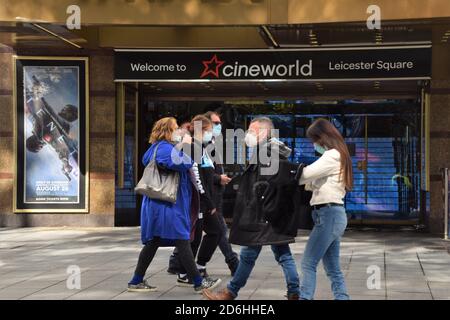 Le persone con maschere facciali camminano oltre il Cineworld Empire Cinema su Leicester Square, Londra. Cineworld ha recentemente annunciato la chiusura dei suoi cinema nel Regno Unito a causa della crisi del coronavirus. Foto Stock