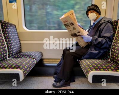 Londra, Regno Unito. 17 ottobre 2020. Un passeggero sulla linea metropolitana che legge un giornale mentre indossa un maschera facciale e guanti. L'uso delle maschere facciali è obbligatorio per viaggiare sul tubo. I casi di coronavirus del Regno Unito sono in aumento e il capitale è passato dal livello di allarme Tier 1 al livello di allarme Tier 2 Covid oggi. Credit: Stephen Chung / Alamy Live News Foto Stock