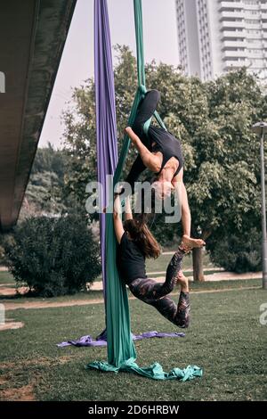 Donne caucasiche che praticano alcune sete aeree posizioni difficili insieme dentro un parco cittadino Foto Stock