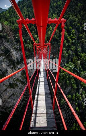 Ponte di legno lungo sopra la gola profonda con una spiaggia di fiume in fondo, tra le rocce. Montagne selvagge nelle Alpi svizzere Foto Stock