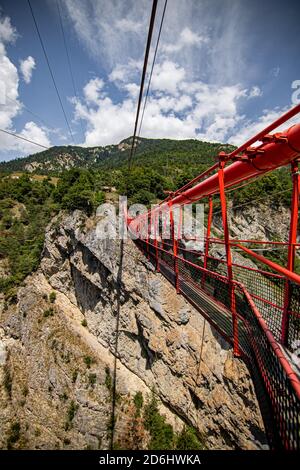 Ponte di legno lungo sopra la gola profonda con una spiaggia di fiume in fondo, tra le rocce. Montagne selvagge nelle Alpi svizzere Foto Stock