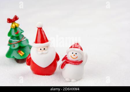 Buon Natale e felice anno nuovo concetto. Cute babbo natale, figura di pupazzo di neve e albero sulla neve con spazio di copia Foto Stock