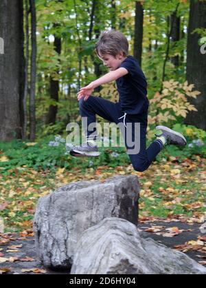 Un ragazzo atletico di 8 anni che salta in alto nel aria Foto Stock