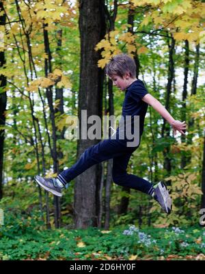 Un ragazzo atletico di 8 anni che salta in alto nel aria Foto Stock