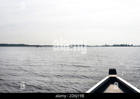 Foto scattata da una barca di legno, persone visibili che galleggiano sulle barche, l'arco della barca è sfocato. Foto Stock