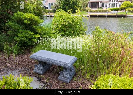 Un giardino del South Carolina nel mese di maggio. Erba bianca di fronte ad una panca di pietra accanto ad un canale. Foto Stock