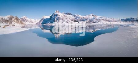 Vasta gamma di vini riflessi nel mare blu, grande strato di ghiaccio, dietro le montagne Blektinten e Andopshesten di fronte al fiordo Foto Stock