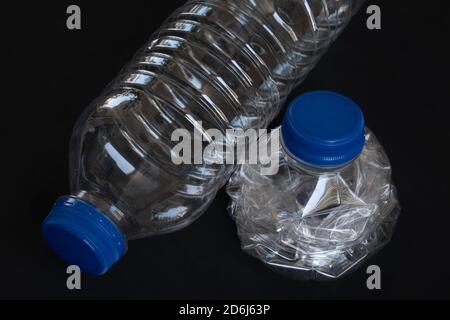 Bottiglie d'acqua in plastica usate e frantumate su fondo nero Foto Stock