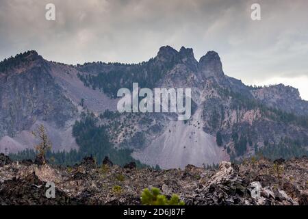 Paulina Peak in piedi alto in un cielo tempestoso con roccia scivola lungo il lato e un grande flusso di lava ossidiana Alla base di Newberry National Volcanic Mon Foto Stock