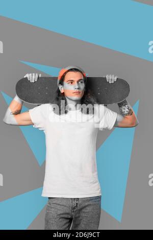Giovane uomo millenario adulto che tiene lo skateboard dietro la testa Foto Stock