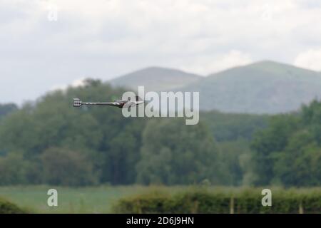 Volando basso e veloce di fronte alle colline di malvern, un telecomando FPV prima persona vista ali è in fuoco selettivo. Elica sfocata. Foto Stock