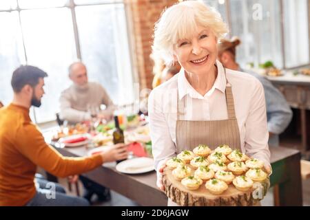 Donna anziana che tiene uno spuntino sulla piastra decorativa Foto Stock