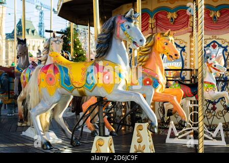 Mosca, Russia - 1 dicembre 2019: I cavalli multicolori della giostra del festival primo piano. Un divertente giro per i bambini, un cavallo giocattolo grigio con una mane nera Foto Stock