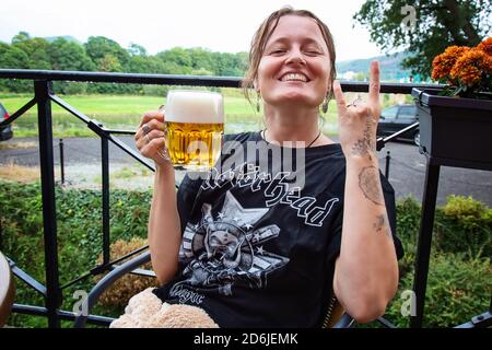 Decin, Repubblica Ceca, 18 agosto 2020: Fan femminile della band Motorhead con birra ceca seduto nel pub-giardino godendosi e sorridendo Foto Stock