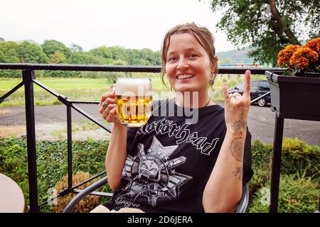 Decin, Repubblica Ceca, 18 agosto 2020: Fan femminile della band Motorhead con birra ceca seduto nel pub-giardino godendosi e sorridendo Foto Stock