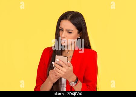 Closeup ritratto sconvolto triste scettico infelice donna gravi in cerca i messaggi di testo sul telefono orinato con isolati di conversazione su giallo di sfondo per studio. Foto Stock