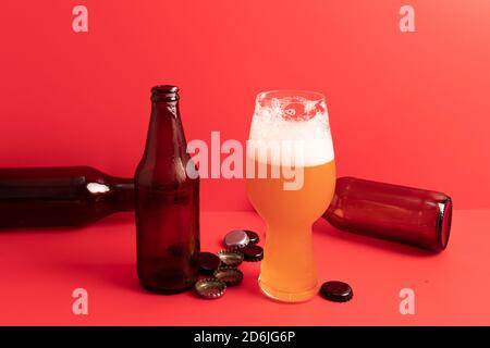 Bicchiere di birra IPA e varie bottiglie con sfondo rosso Foto Stock