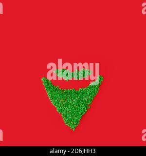 Babbo Natale concetto minimo. Natale Capodanno appartamento Lay. Barba divertente di verde dolce spruzzi su sfondo rosso tradizionale, concetto creativo minimo Foto Stock