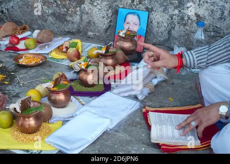 Un sacerdote indù a Banganga Tank, Mumbai, India, recita i versi di un libro di preghiera come parte di riti memoriali (sharaddha) per una donna deceduta Foto Stock