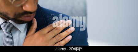 Uomo africano spazzolando Dandruff da vestito sporco Foto Stock