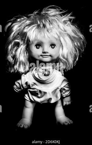 Faccia creepy della bambola della ragazza. Sembra un personaggio di film horror. Bambola infuriata, paura di un fantasma vivente. Concetto di Halloween. Scatto in bianco e nero, basso-KE Foto Stock