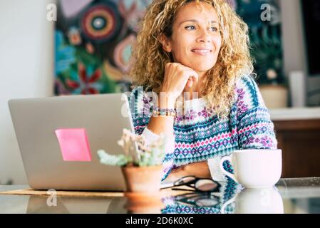 Ritratto di bella donna caucasica bionda sorriso e lavoro con computer portatile a casa - concetto di ufficio alternativo e. libertà con il lavoro intelligente t Foto Stock