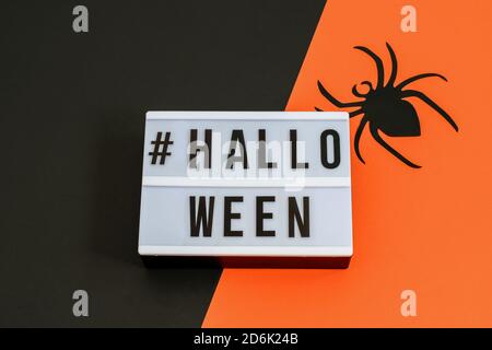 Ragno decorativo su sfondo nero-arancione. Invito alla festa, sfondo di Halloween, vista dall'alto. Foto Stock