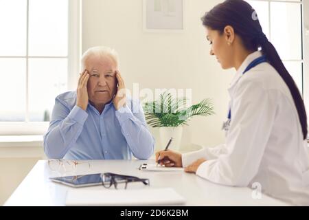 L'uomo anziano si lamenta di mal di testa, stress o vista offuscata durante il colloquio medico Foto Stock